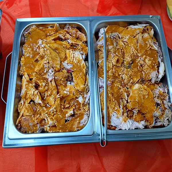 Texto alternativo: Rechaud duplo de metal sobre toalha vermelha, com carne de porco desfiada em molho e um pegador.